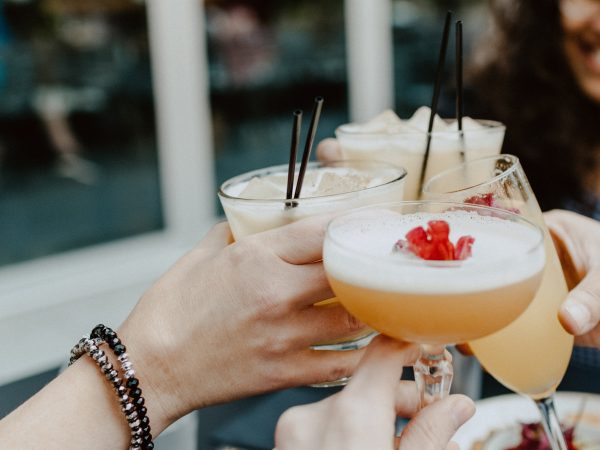 Multiple people drinking different cocktails and clinking them together.