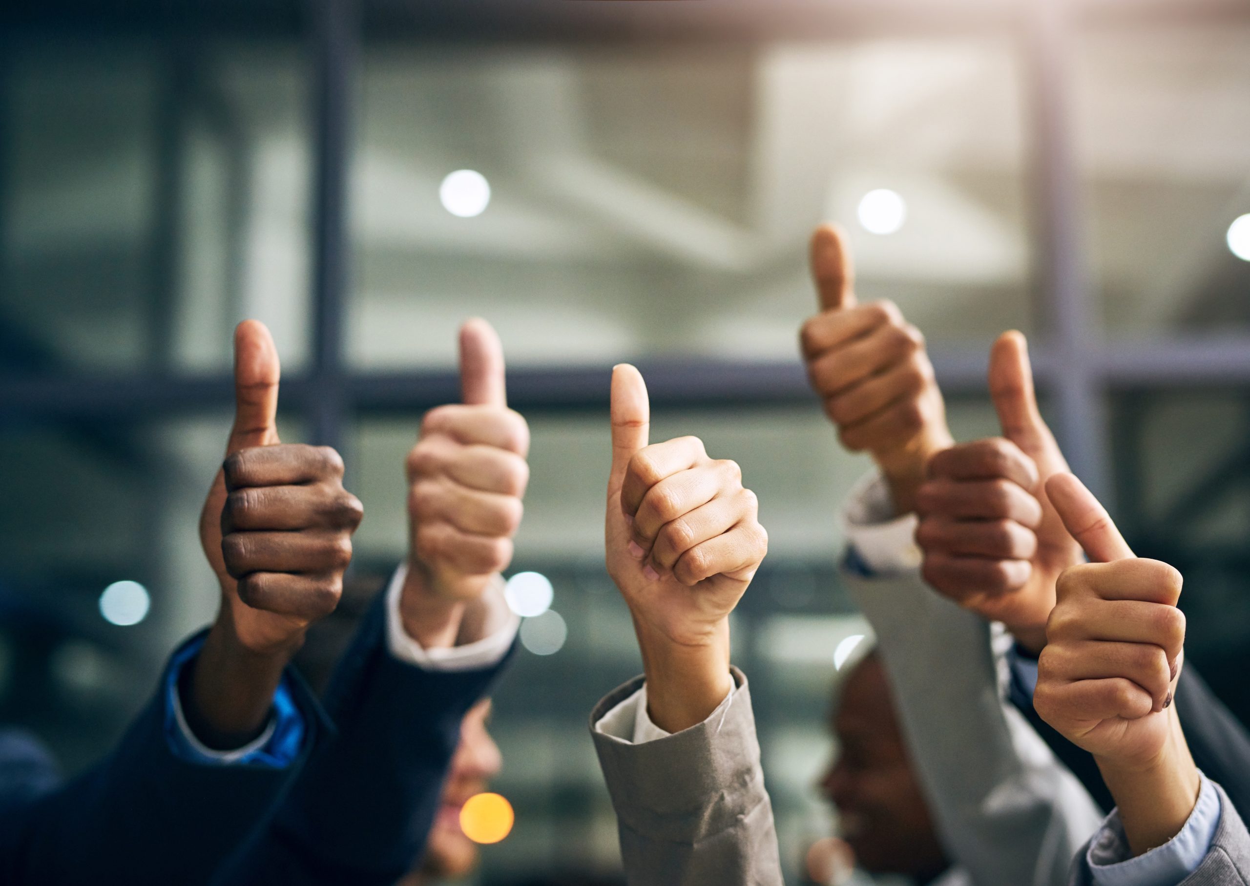 Hands showing thumbs up with business men endorsing, giving approval or saying thank you as a team in the office.